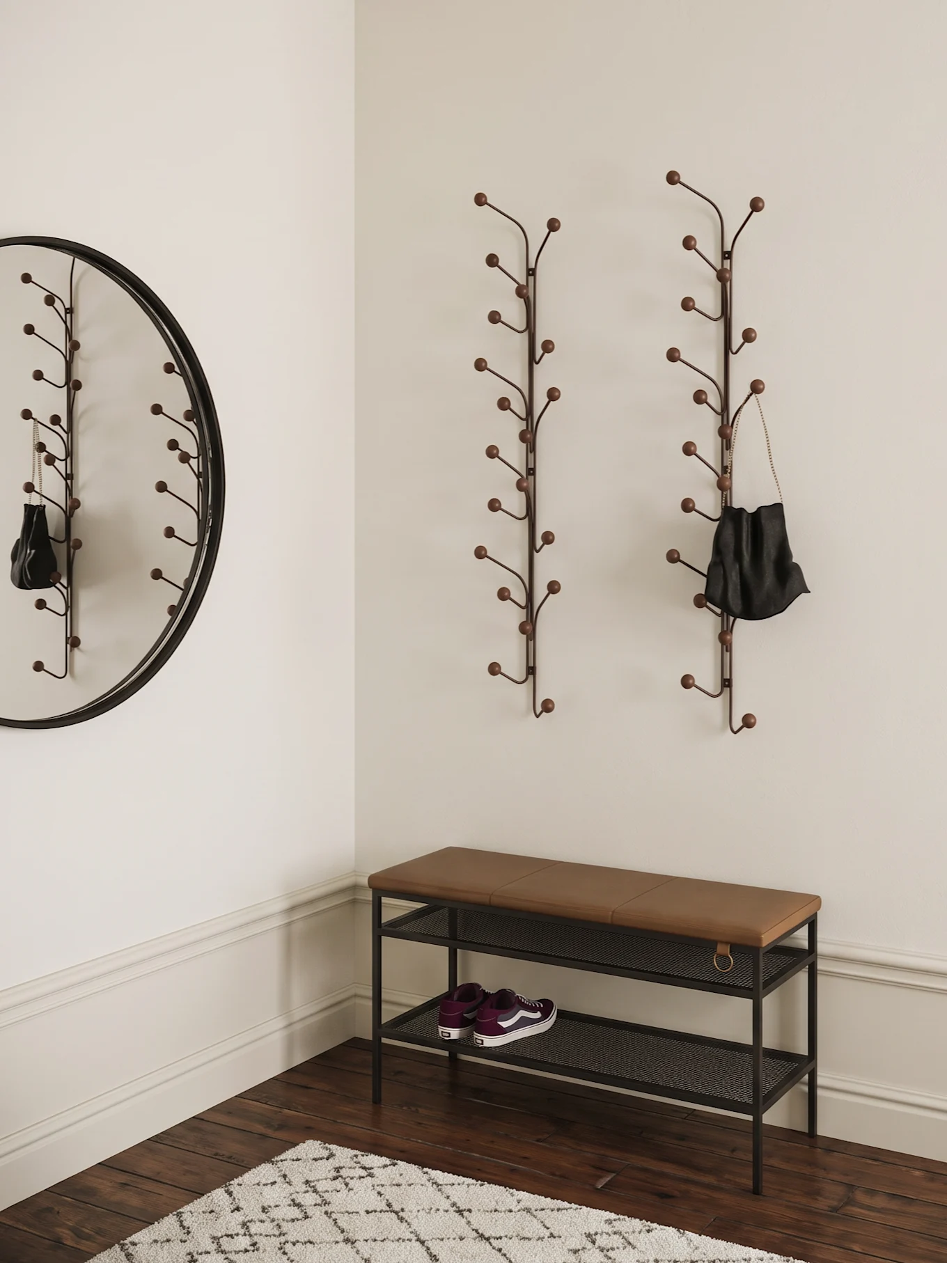 Entryway with two branch-like coat racks, a round mirror, a brown bench with purple sneakers, and a rug.