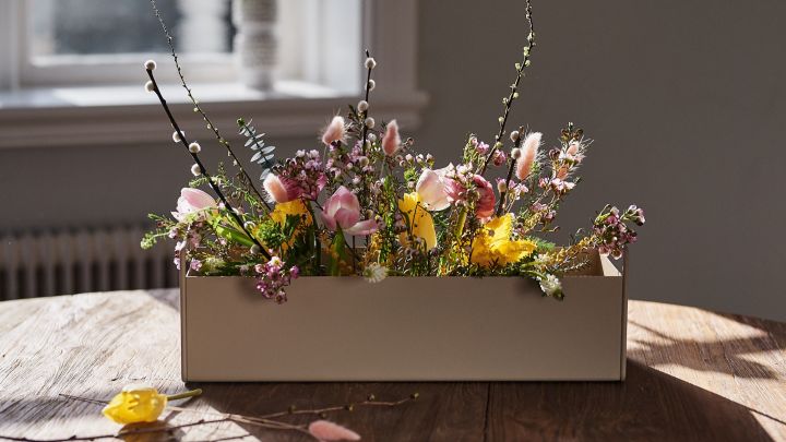 Small beige Plant Box from Ferm Living stands on the table with spring flowers in it for interior design inspiration for spring. 