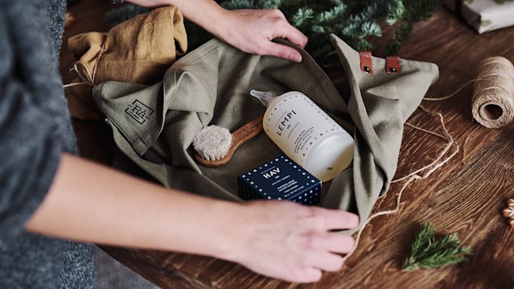 A gift set of soaps and brushes is wrapped in a tea towel to be packaged as a zero-waste gift.