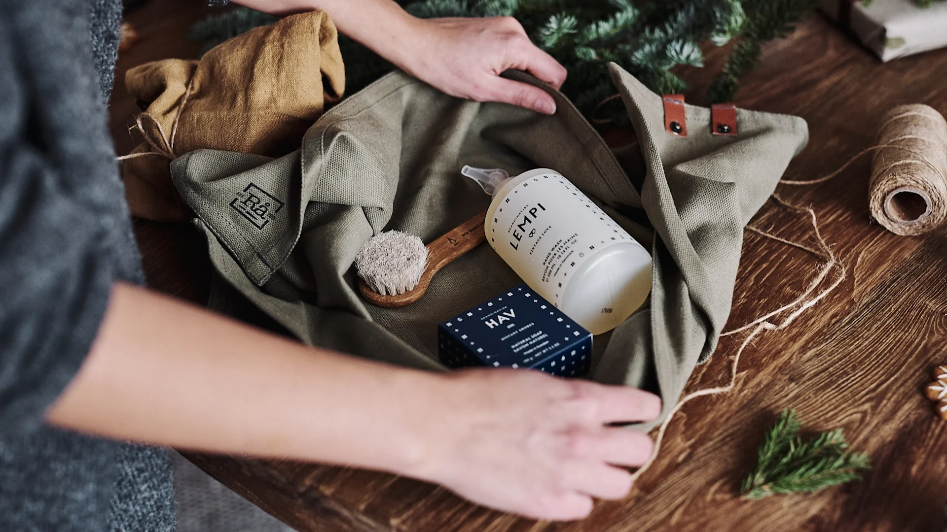 A gift set of soaps and brushes is wrapped in a tea towel to be packaged as a zero-waste gift.