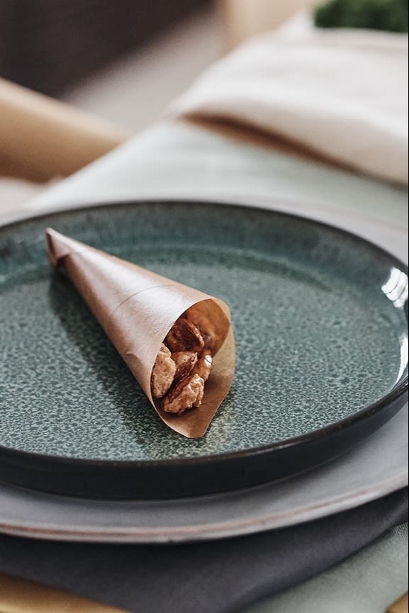 Candied almonds in waxed paper cones are placed on the plate on the Christmas table as a welcoming gesture to the guests.