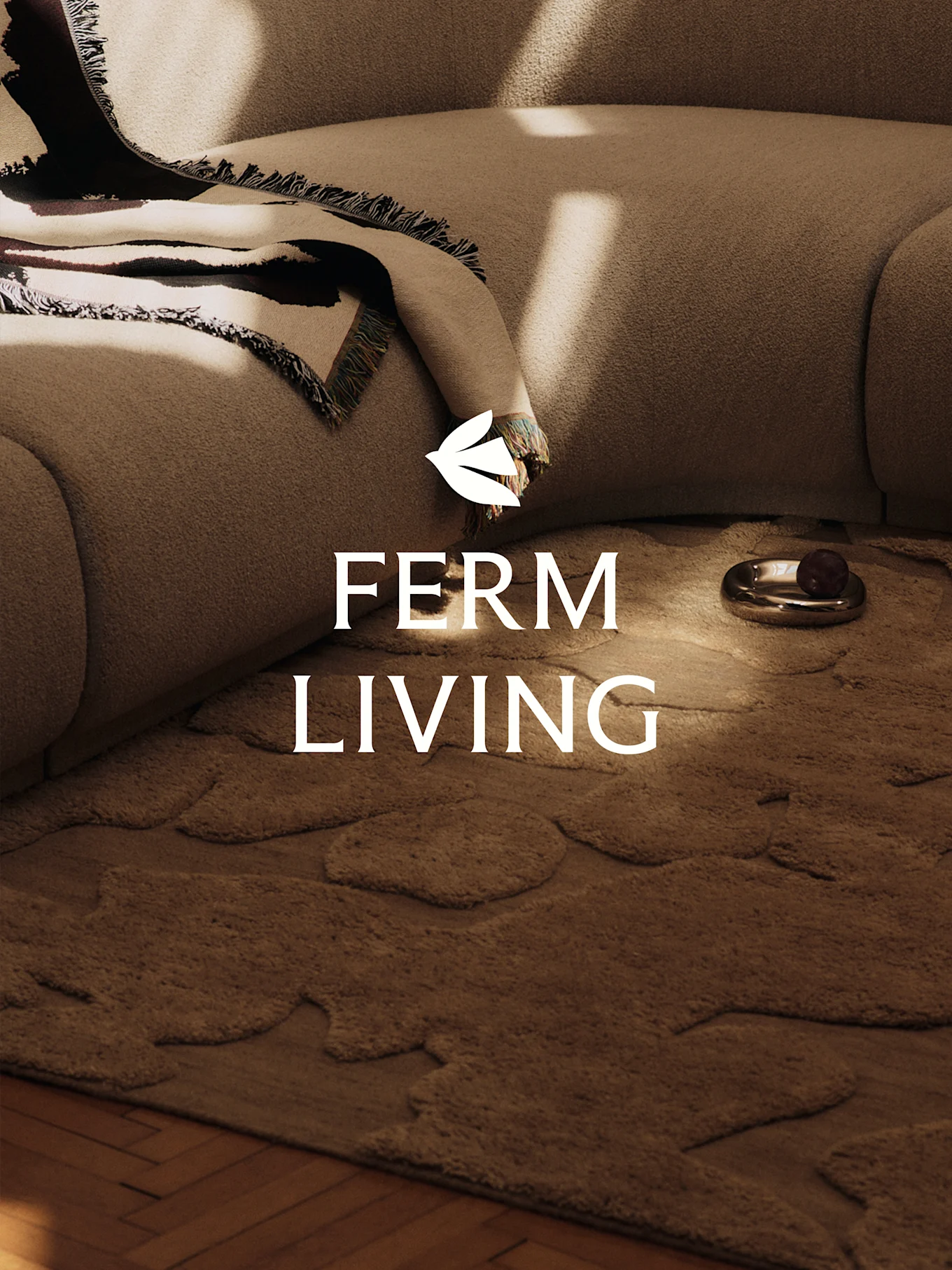 A cozy scene with a light brown textured sofa, a patterned blanket, a brown rug with organic shapes, and a decorative dish.