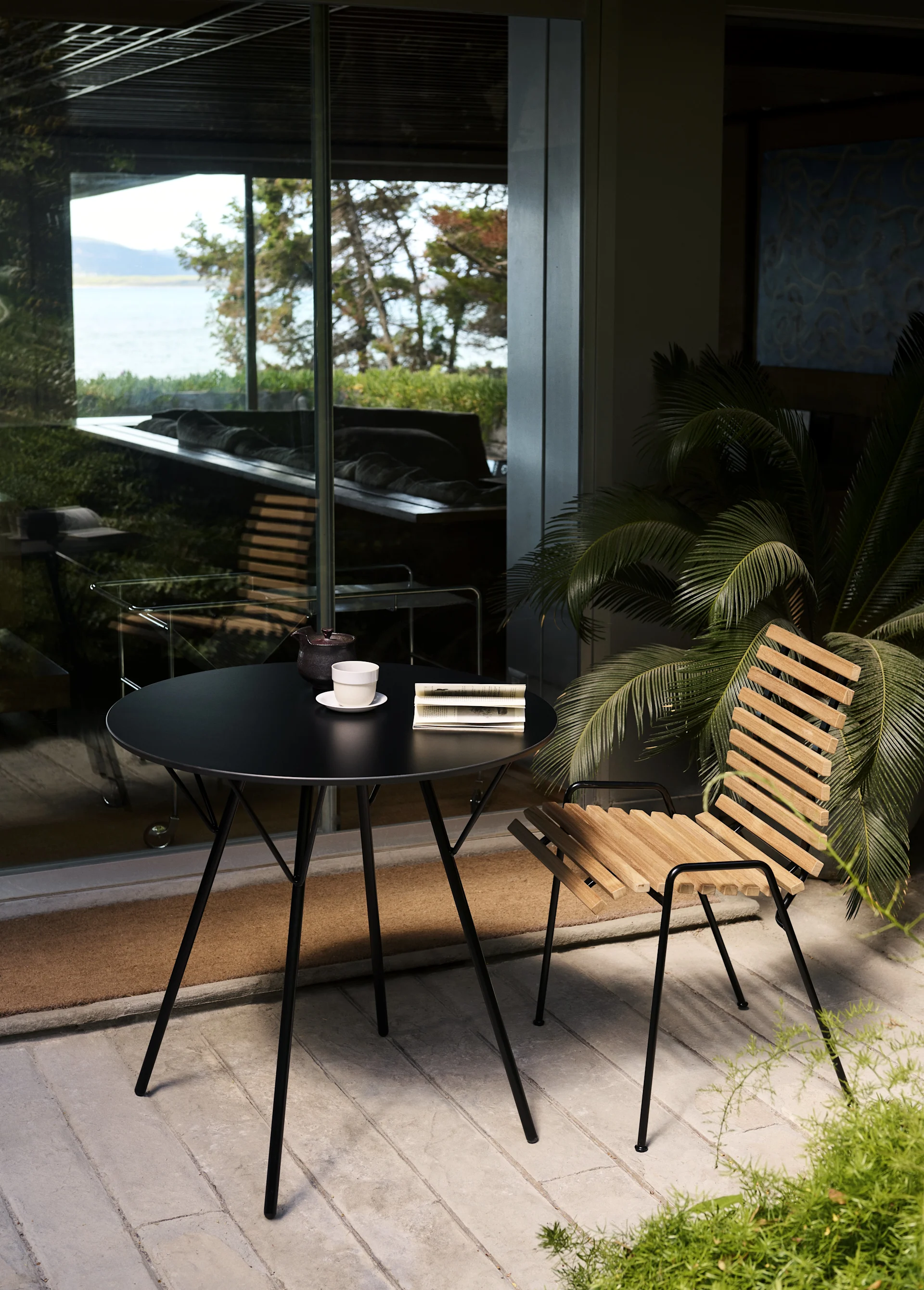 The RFH RD4 patio side chair from &Tradition stands on a patio with a round table.