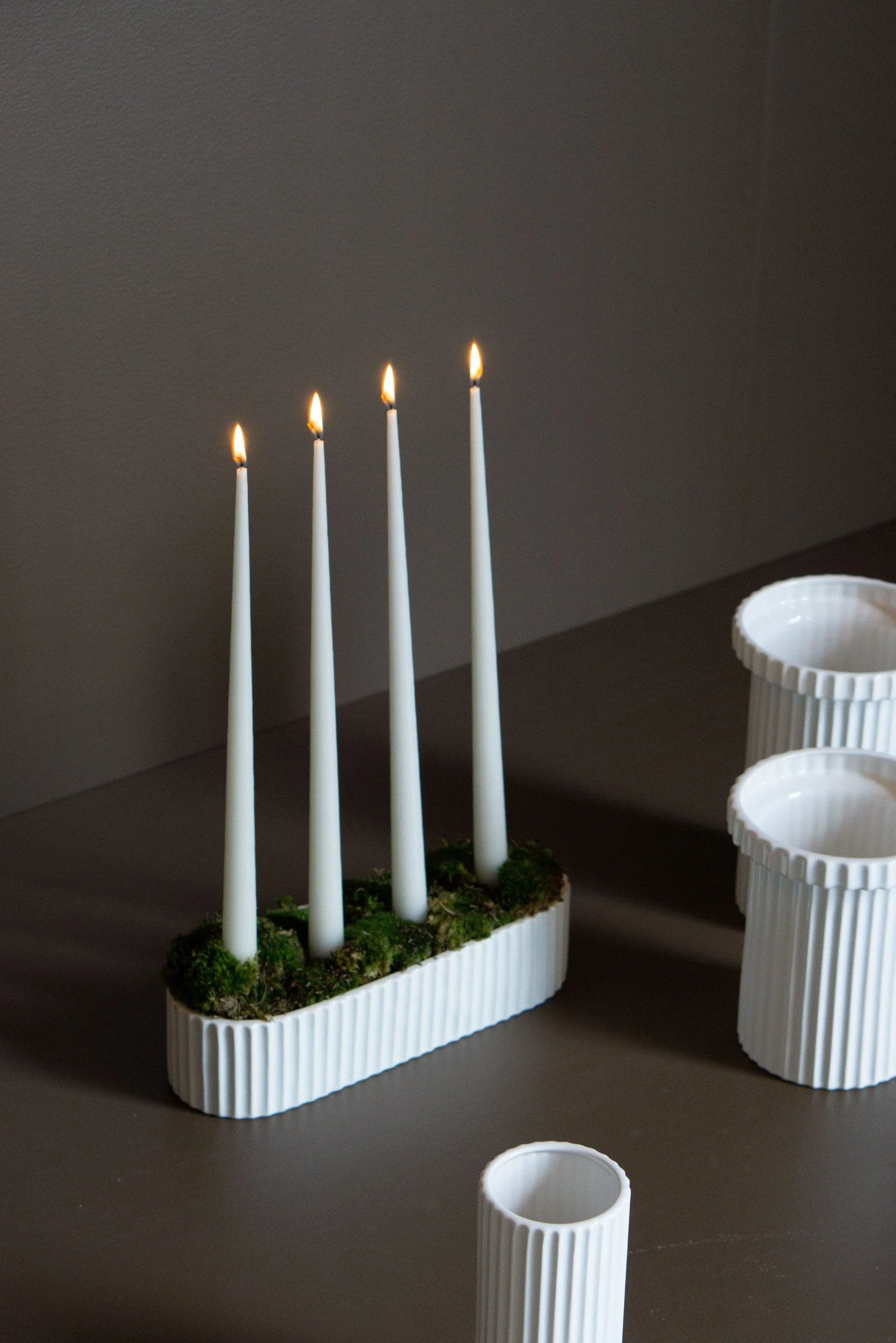 An Advent candle holder with real candles, decorated with green twigs and moss.