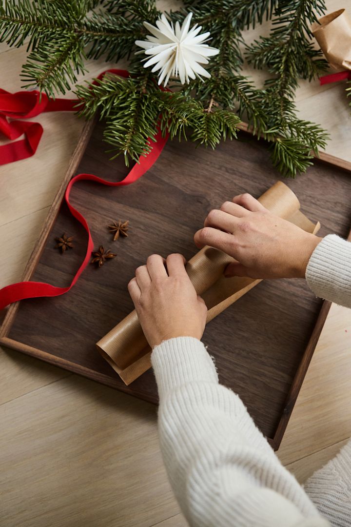 Step two in making your own Christmas cracker, roll the paper around the toilet roll. 