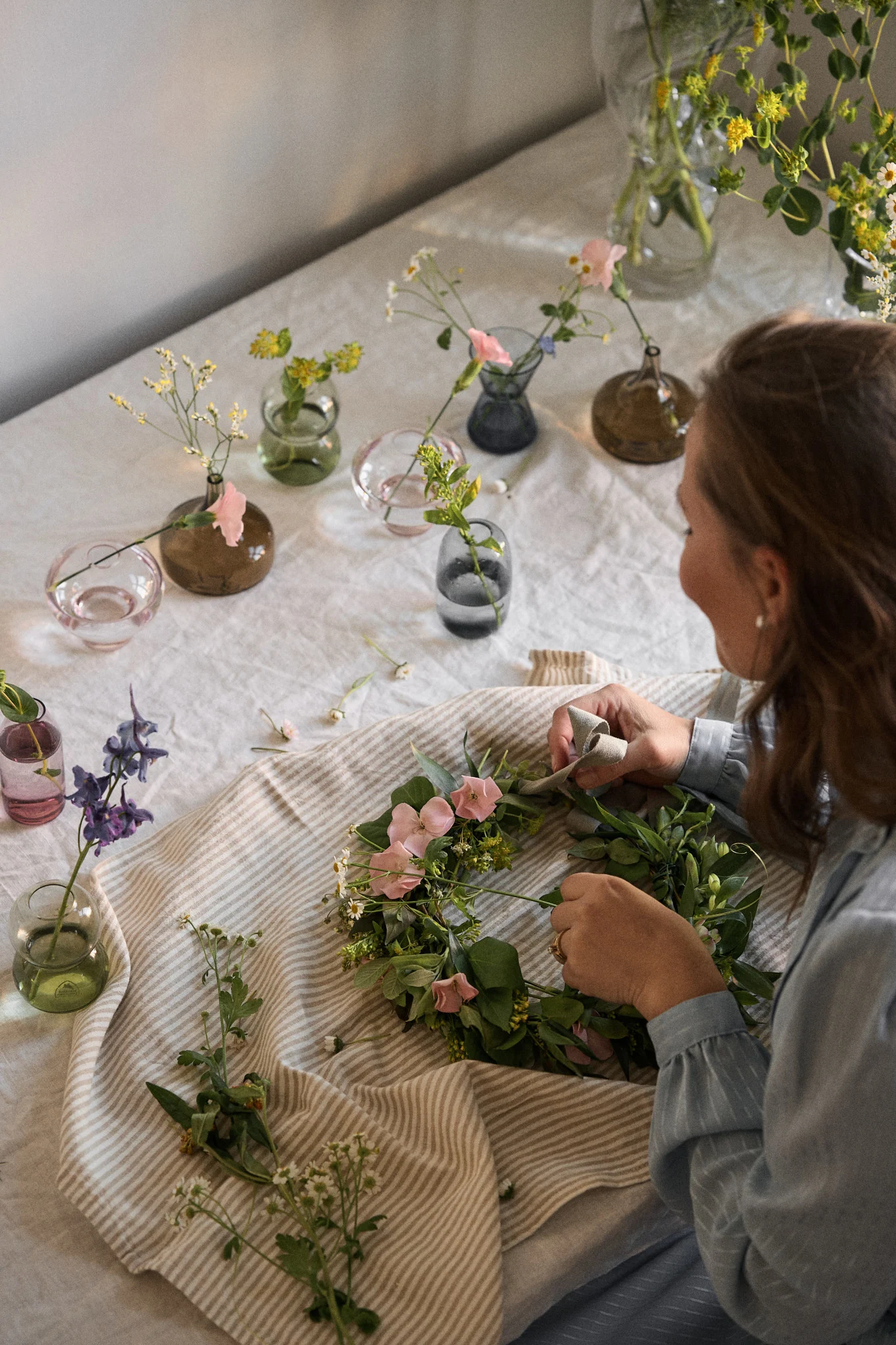 A woman makes a handmade flower crown, an essential Swedish midsummer party idea.