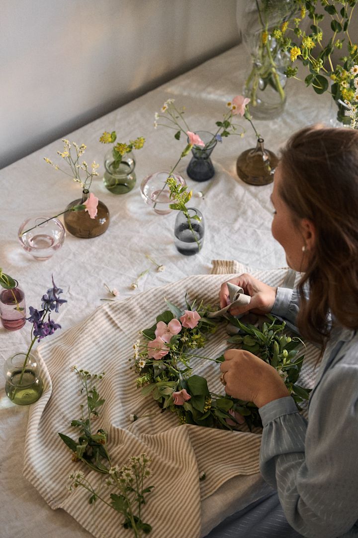 A woman makes a handmade flower crown, an essential Swedish midsummer party idea.