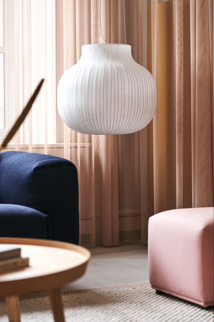 The white Strand ceiling lamp hangs above colourful and contrasting pieces of furniture.