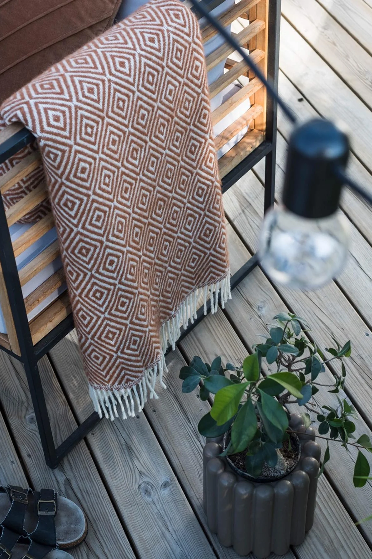 The brown Mist flowerpot from DBKD stands on the terrace next to a bench with a blanket in @lindaz.se's home.