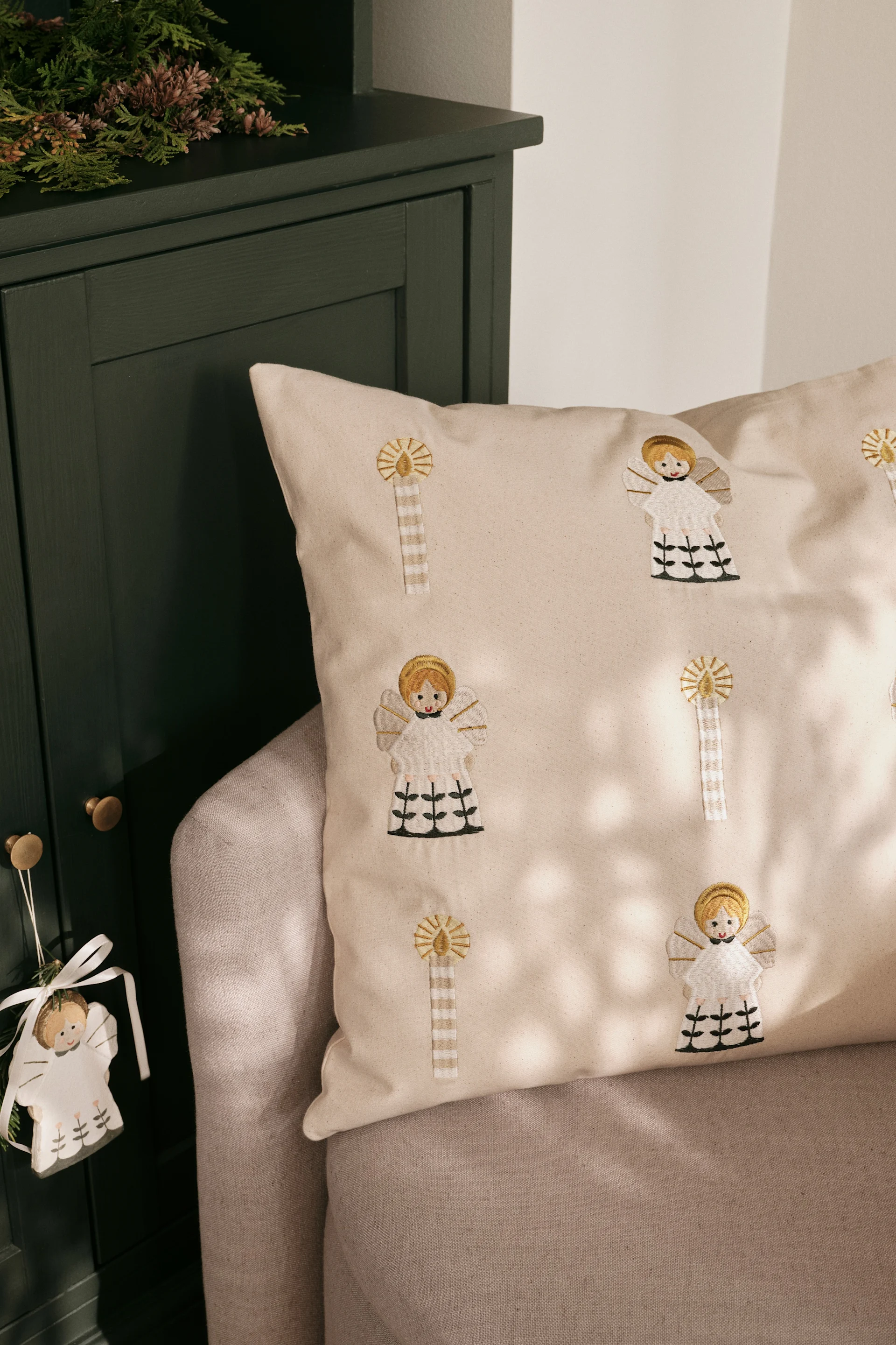 The enchantingly embroidered cushion cover from Broste Copenhagen, shown here on a sofa, is one of the trends in Christmas decorations for 2025.