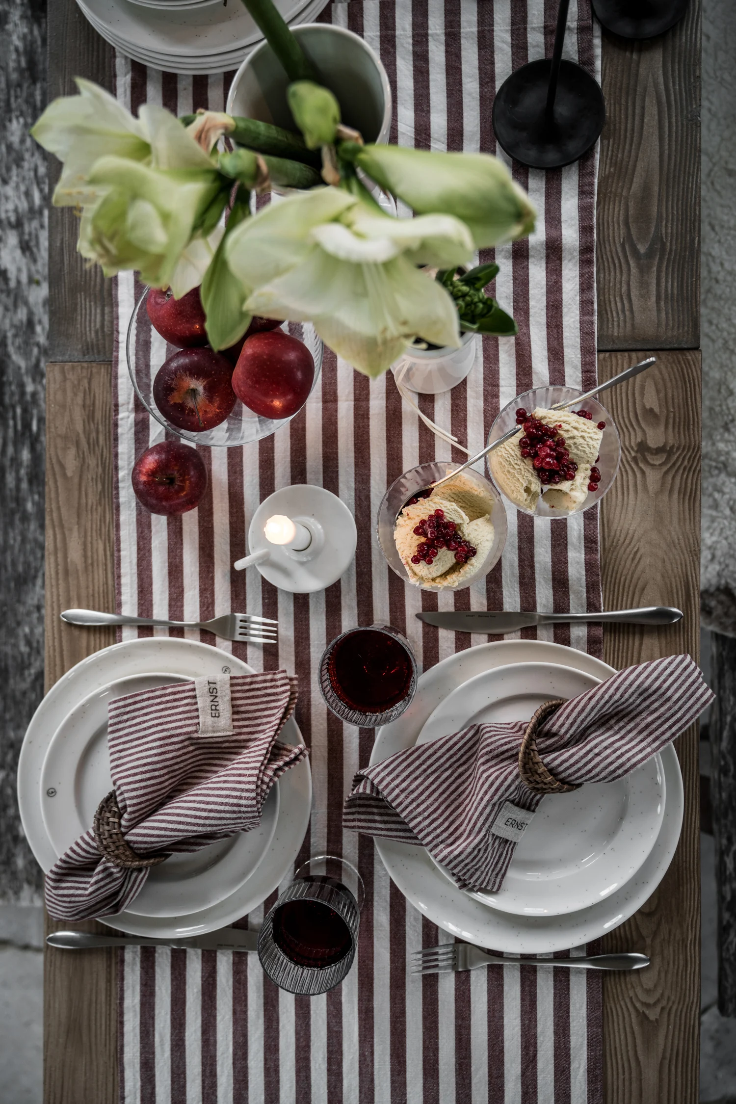 A table set with crockery, a jug, candlesticks and Ernst's green and white striped tablecloth.