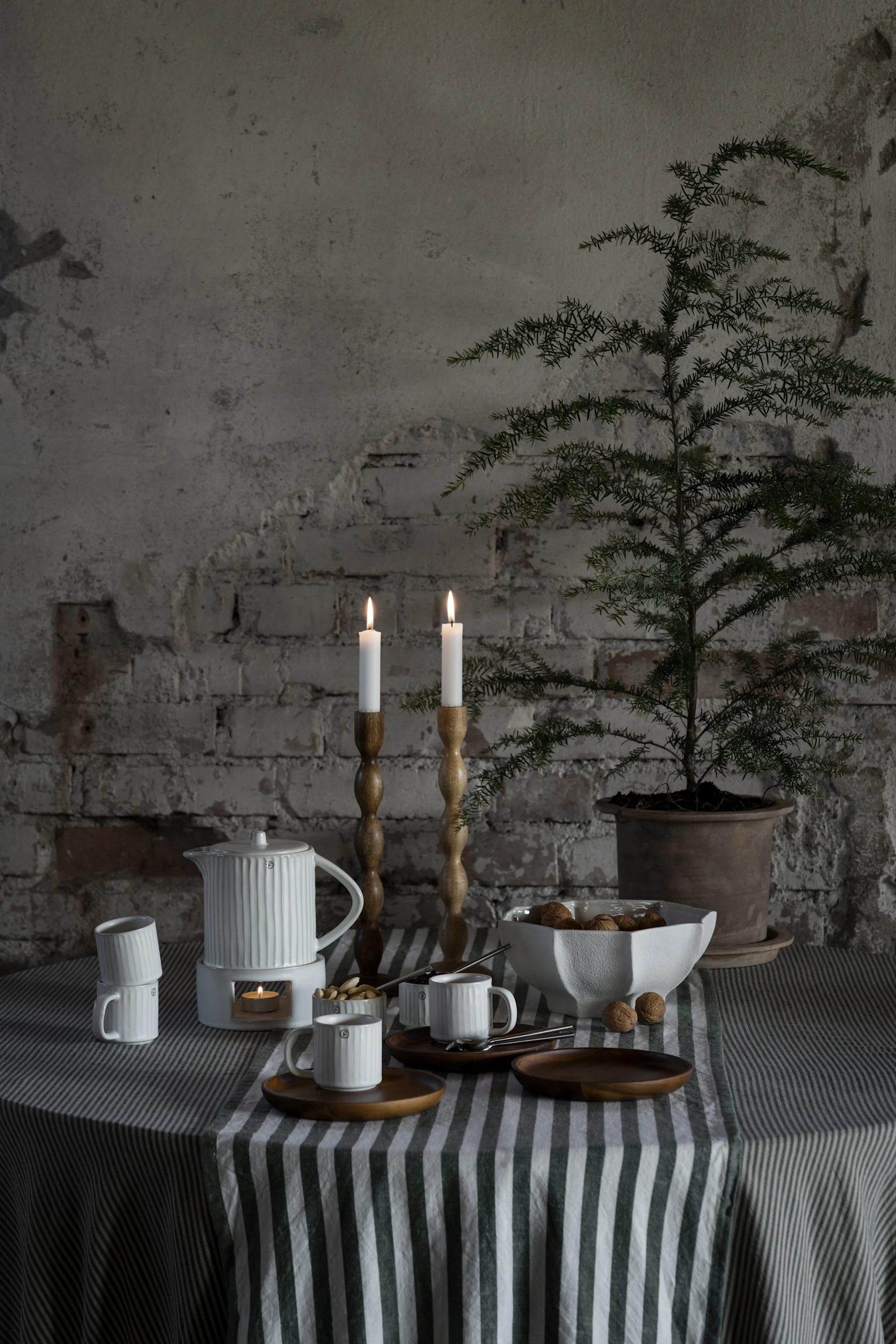A table set with crockery, a jug, candlesticks and Ernst's green and white striped tablecloth.