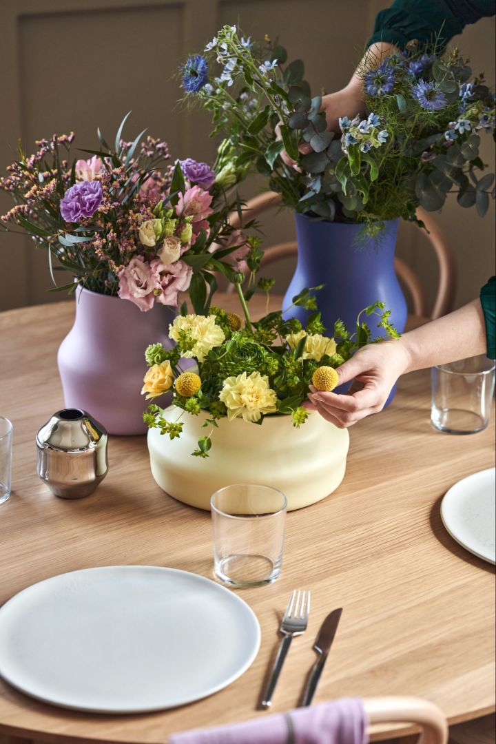 A hand adjusts the flowers in the Dorotea vases, designed by Monica Förster for Gense. 