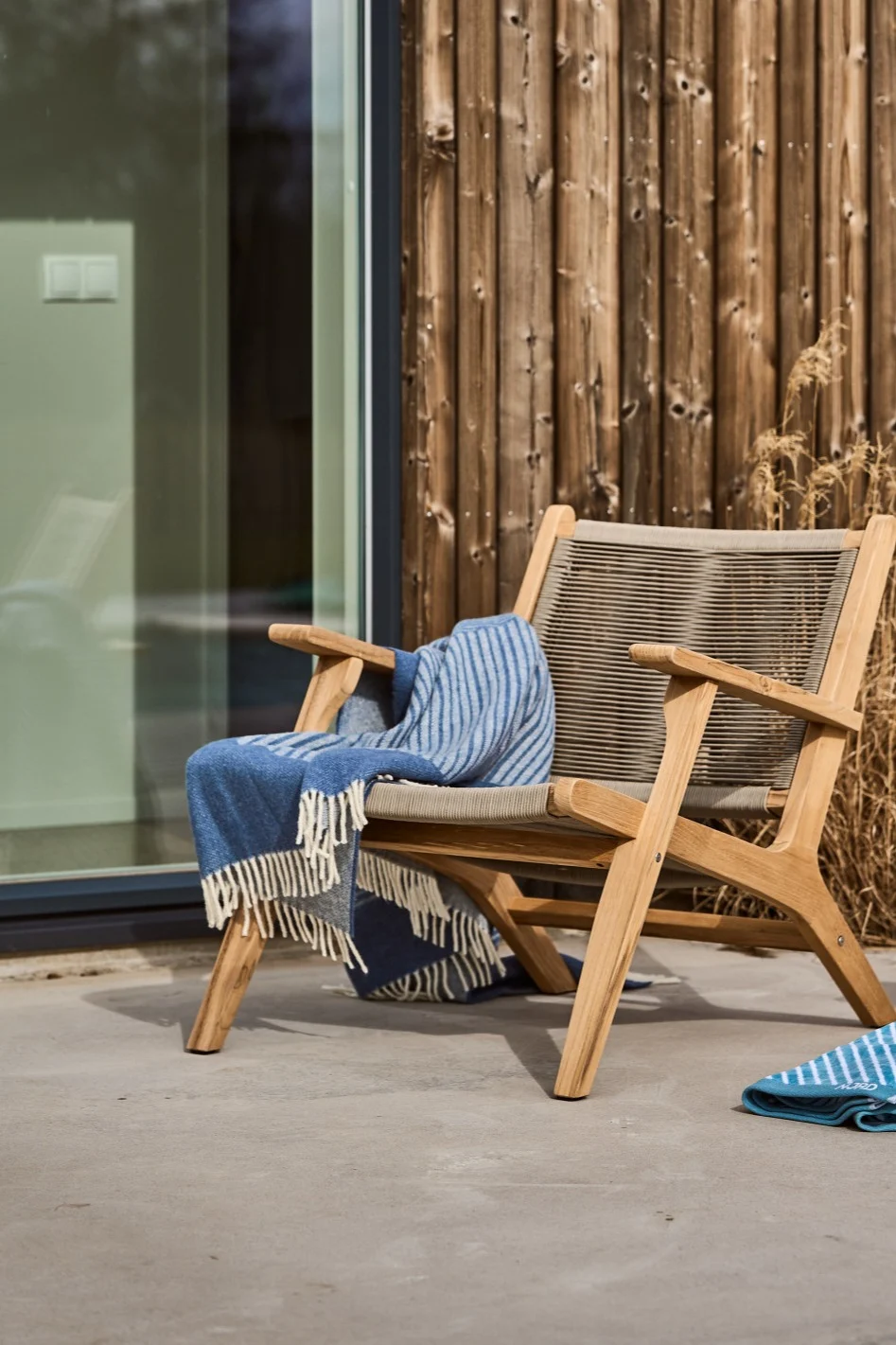 A Scandinavian terrace with the Sandvik lounge chair from 1898 and the blue Stripes woollen blanket from NJRD.