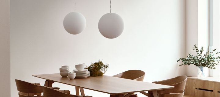 The Design House Stockholm Luna lamp hanging in a pair above a wooden dining table. 