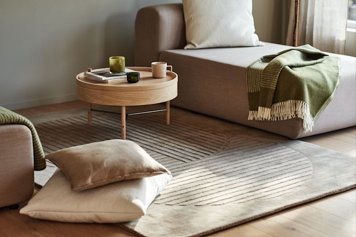 A living room with a beige carpet and green wool throws from the NJRD Edges collection.