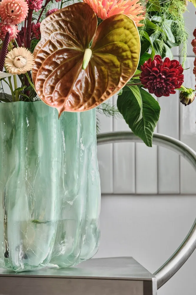 Blue, cracked vase from Kosta Boda with a bunch of flowers.