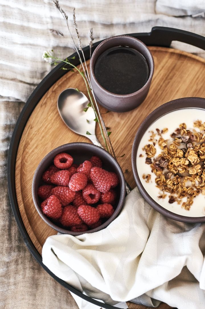 A luxury breakfast in bed served on a beautiful tray from Eva Solo with berries and muesli from brown bowls from Ferm Living.