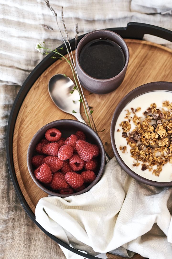 A luxury breakfast in bed served on a beautiful tray from Eva Solo with berries and muesli from brown bowls from Ferm Living.