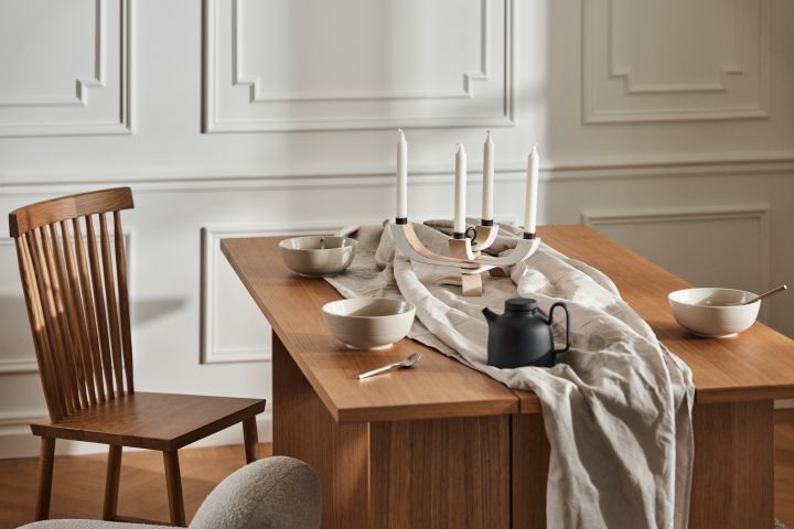 Stylish dining area with wooden table from Design House Stockholm, Family chair, linen cloth and porcelain in the form of bowls and teapot in black.