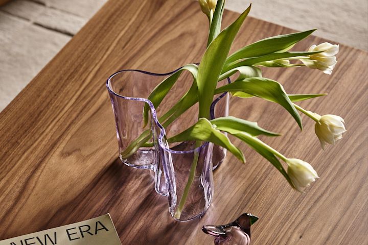 The Aalto vase in light pink with white tulips on a coffee table with a glass bird figurine and a magazine. 