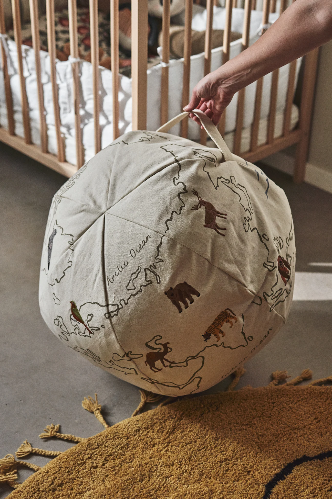 A world map and bean bag in one, here you see a hand holding the World pouf from Ferm Living, a great idea for a children's room. 