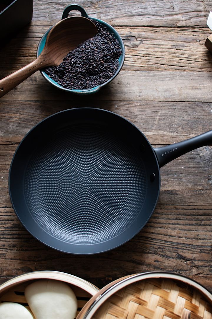 Satake's frying pan stands on a dark wooden table.