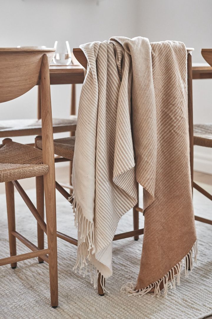 The Scandi Living Mist throw in cotton that gradually changes between different tones of beige, hangs over a dining chair - one of our 7 beige interior design favourites to invest in this autumn.