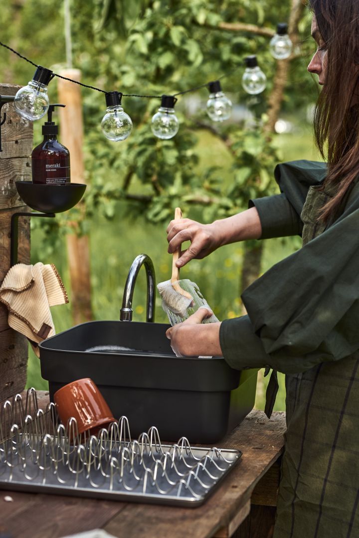 A woman washes up at her simple DIY outdoor kitchen using a portable washing bowl from Brabantia. 