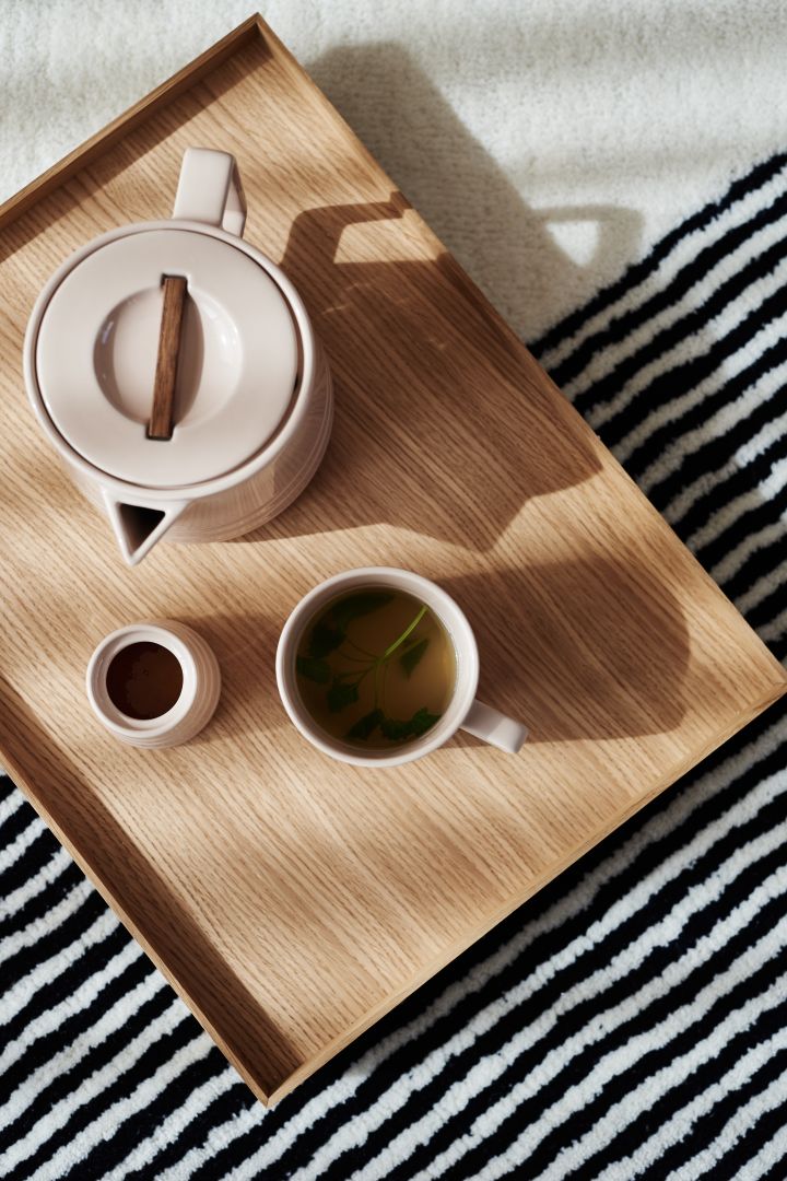 The NJRD Lines teapot, mug and sugar pot from above on a wooden tray with the Lines rug underneath. 