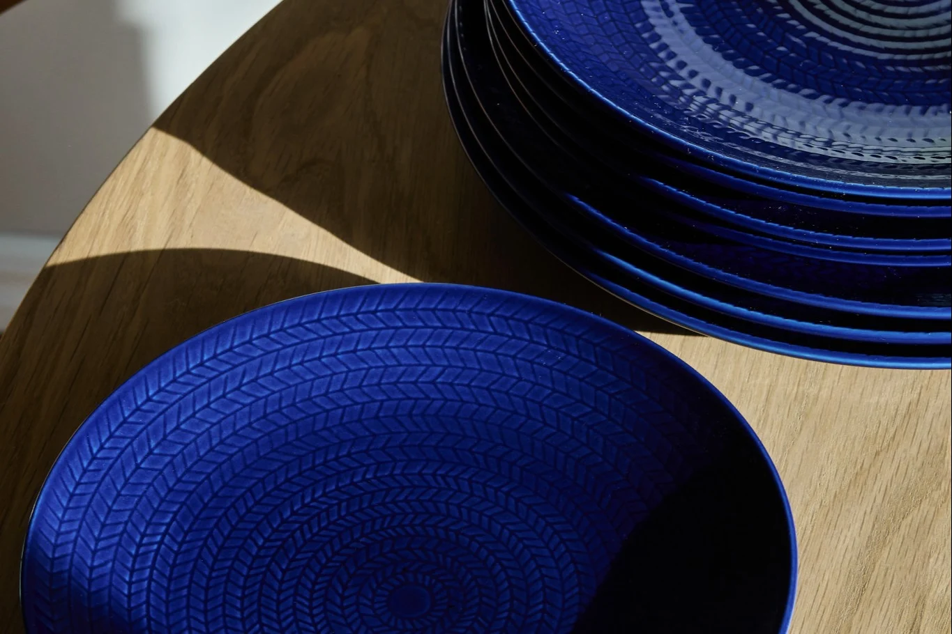 Deep blue plates with a concentric braided pattern on a wooden table.