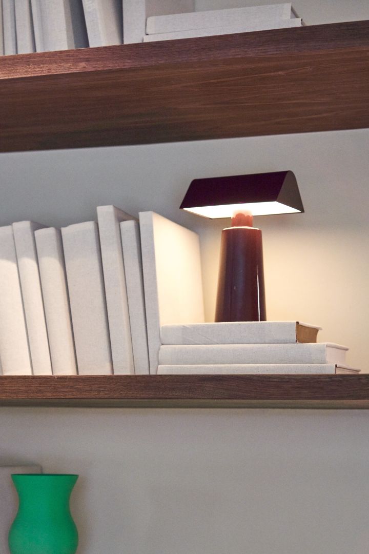 Here you see the Caret MF1 portable table lamp from &Tradition in the colour dark burgundy lighting up a bookshelf. Cordless lighting is one of the top interior design trends for autumn 2022. 