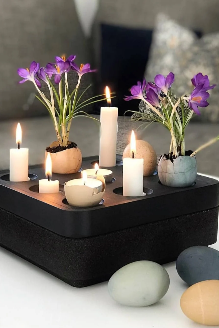 A black Stumpastaken candle holder from Born in Sweden is decorated with candles and coloured eggs with flowers inside for Easter. @dallasvillan
