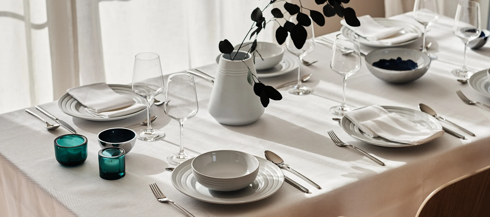 An elegant white table setting with crisp white napkins and tablecloth and clean white porcelain from NJRD.