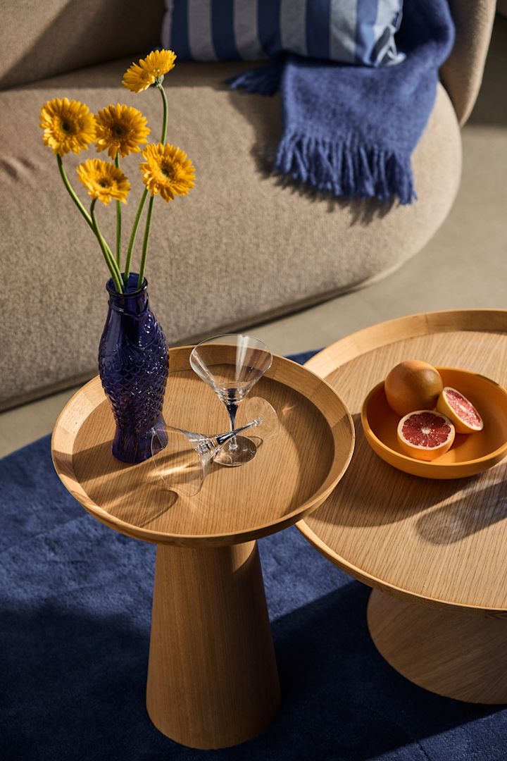 The interior design trends for autumn 2023 are colourful and daring, like here with blue accents in a playful decor with a vase shaped like a fish and sunflowers in it.