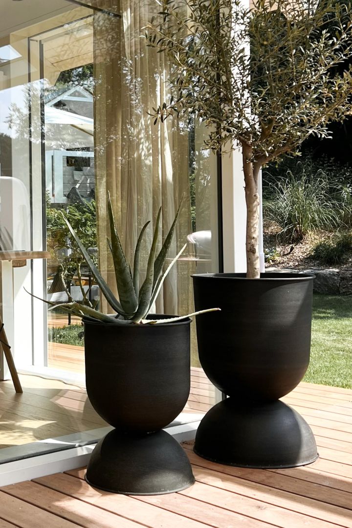 The large outdoor planter Hourglass from Ferm Living stands in a pair together on the deck of 