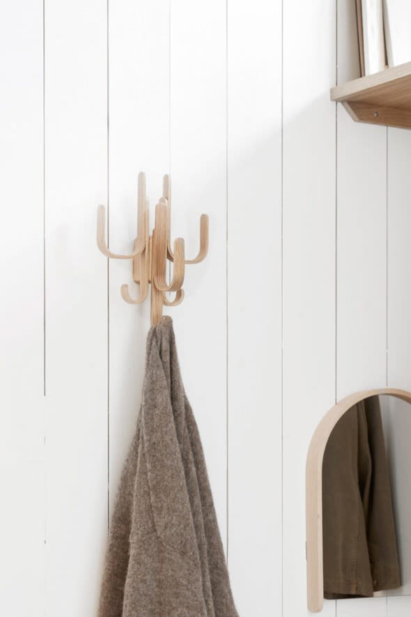 A cardigan hangs on the Woody hook three in oak against a white wall. 