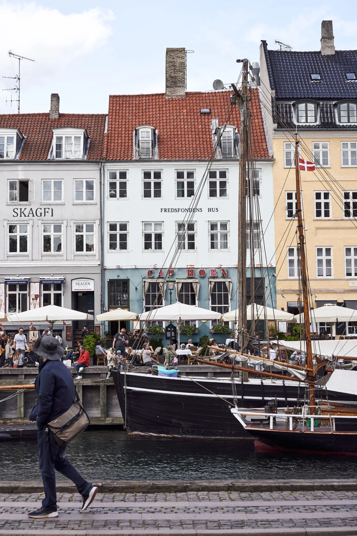 The harbour at Nyhavn is a must-visit on any Copenhagen city tour. Here you see someone walking past the colourful buildings in the habour.