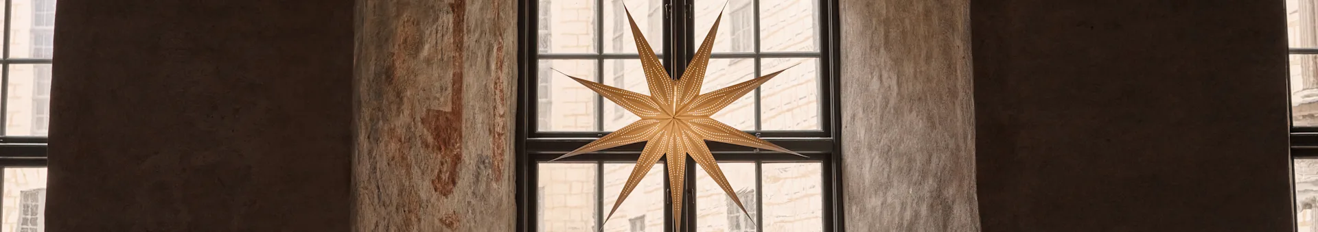 A star-shaped lantern hangs in an arched window, with ornate patterns on the stone walls and archway.