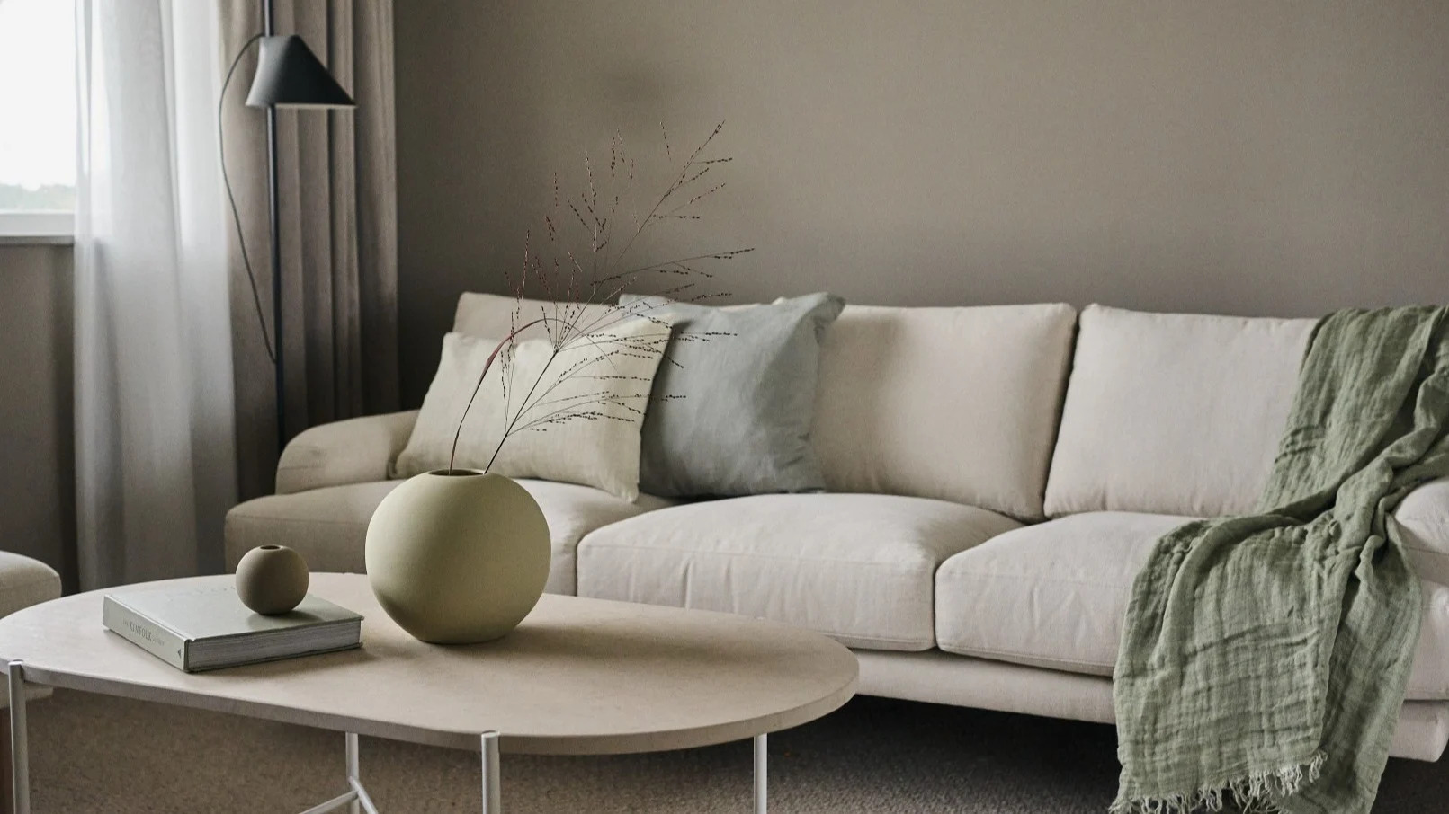 Two versions of the Ball vase from Cooee Design stand on a coffee table in a Scandinavian living room.