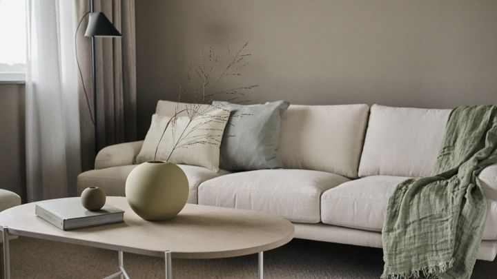 Two versions of the Ball vase from Cooee Design stand on a coffee table in a Scandinavian living room. 