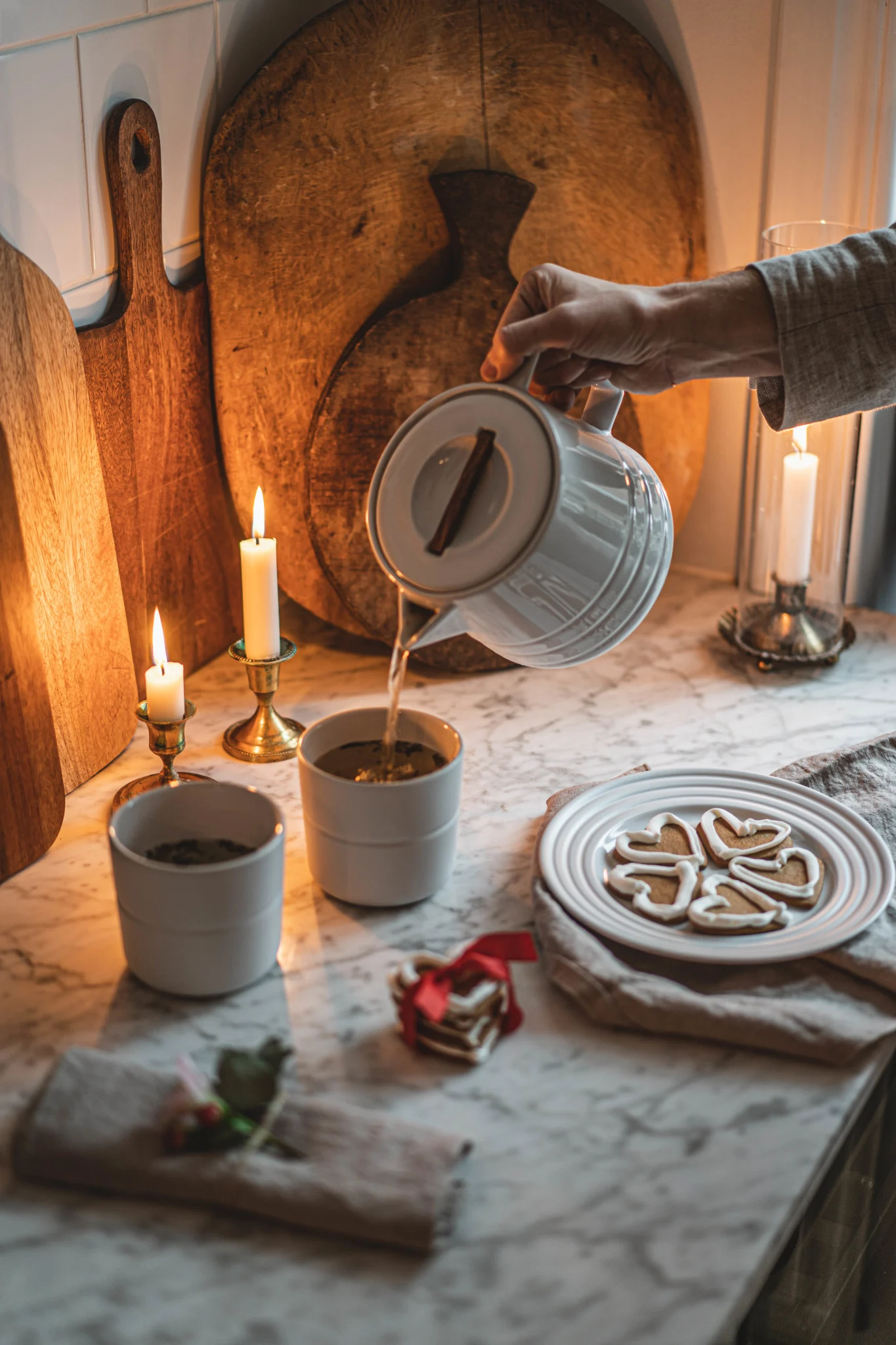 In a cosy kitchen, there is a plate of gingerbread and tea is being poured from a pot into cups. The tableware is from the Lines collection by NJRD.