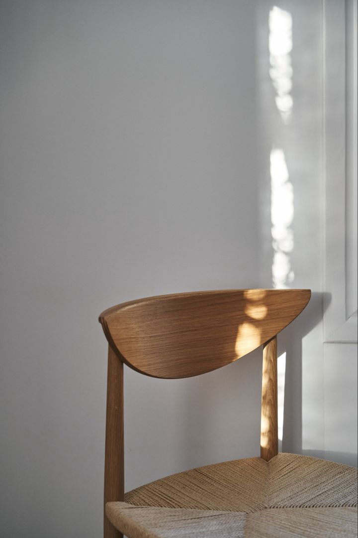 The Drawn dining chair from &Tradition  standing against a white wall in the sunlight.