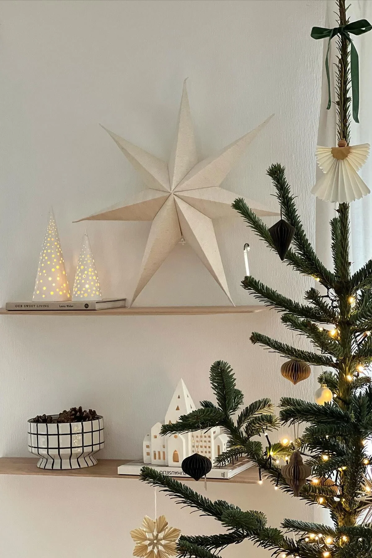 A paper Christmas star from Scandi Living stands on a shelf with other minimalist Christmas decor. 