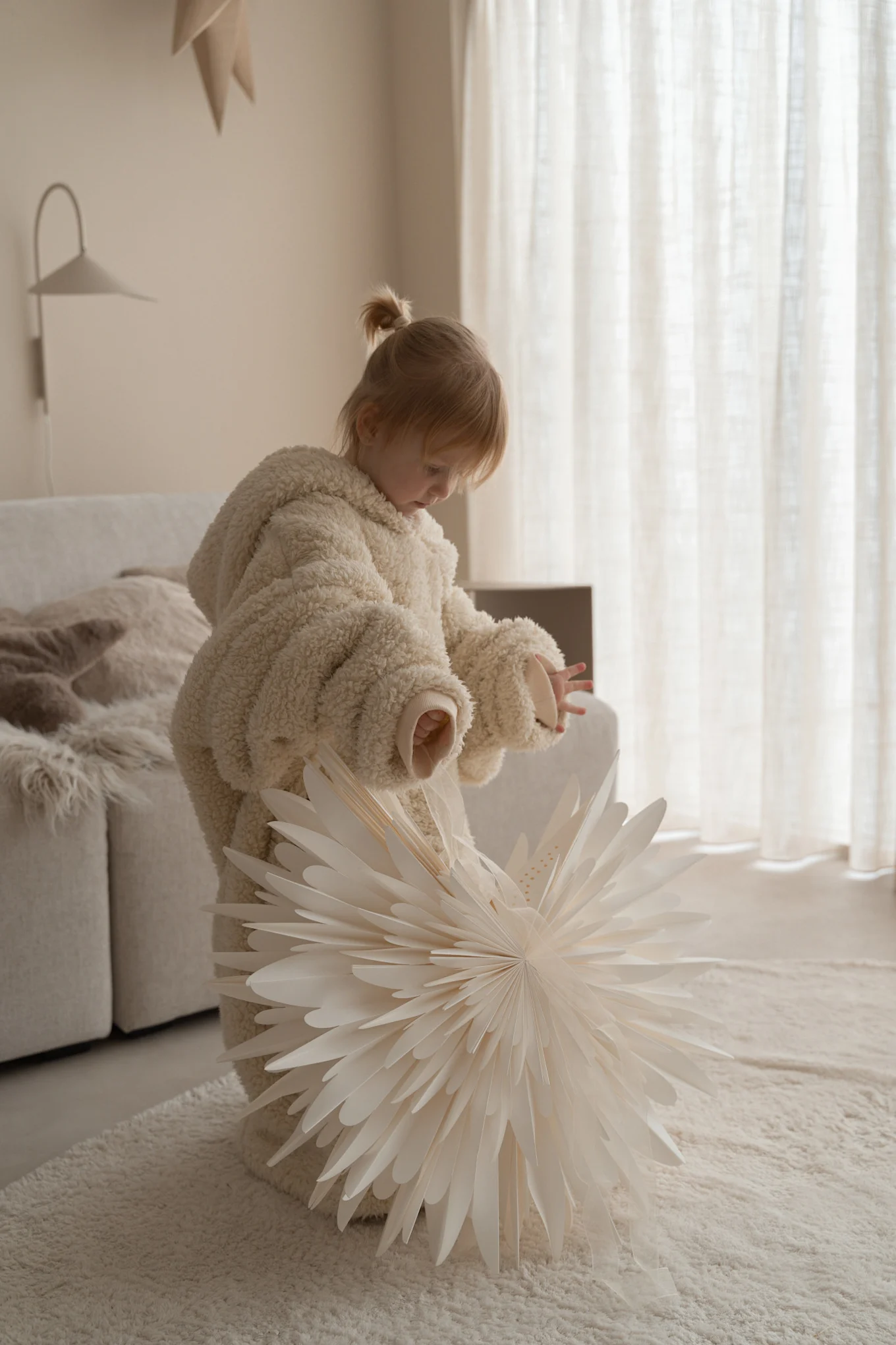 A child holds a paper Christmas star from Scandi Living in a minimalist Scandinavian home. 
