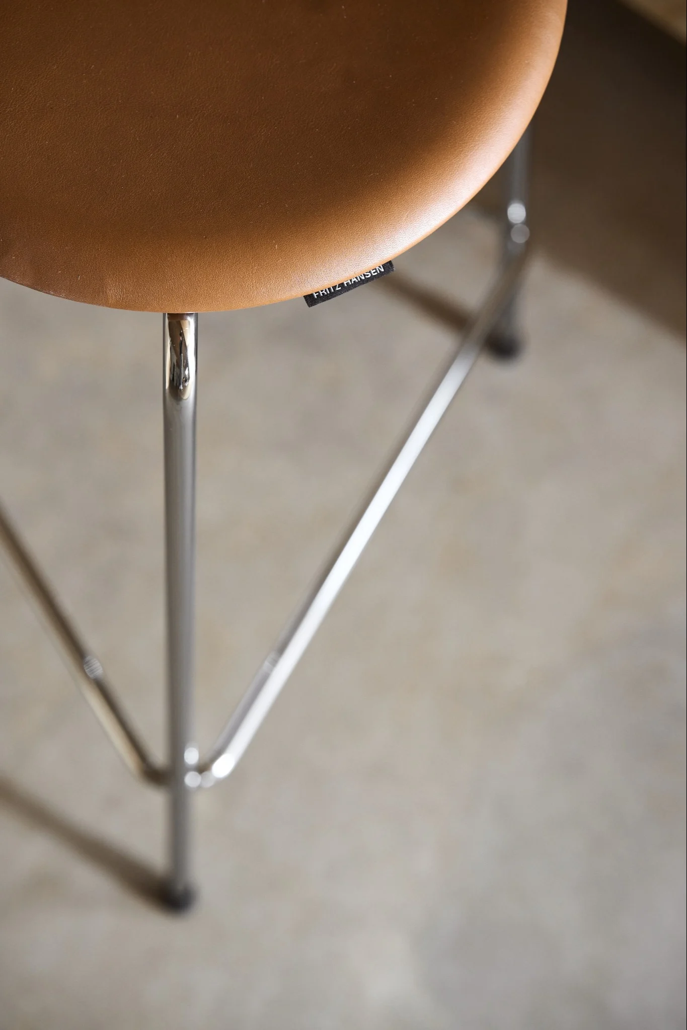 A close up of the Dot bar stool from above in leather and steel in the colour of the walnut.