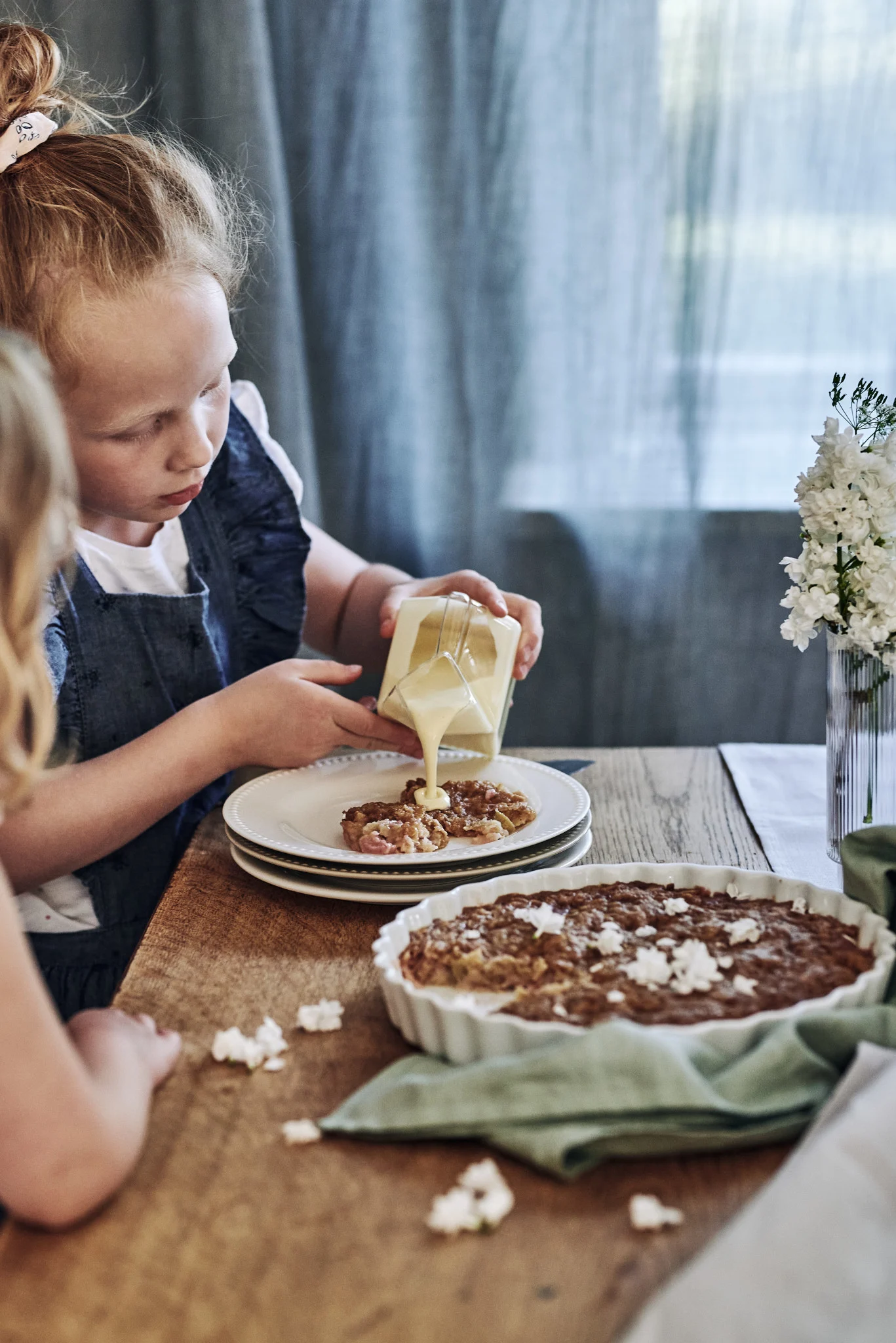 Baking a rhubarb pie should be on any summer bucket list. Here you see a child pouring custard on a homemade pie.  