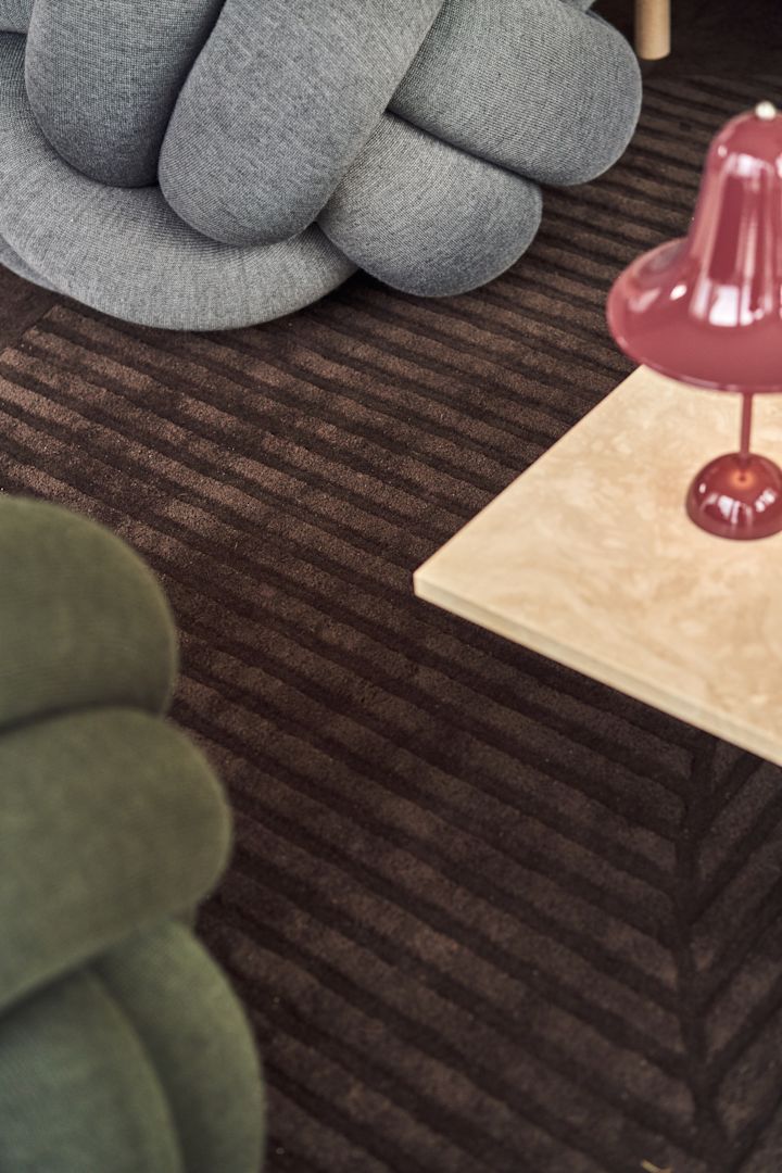 Close up of the Knot Cushion in grey XL and green medium with the ruby red table lamp from Verpan. 