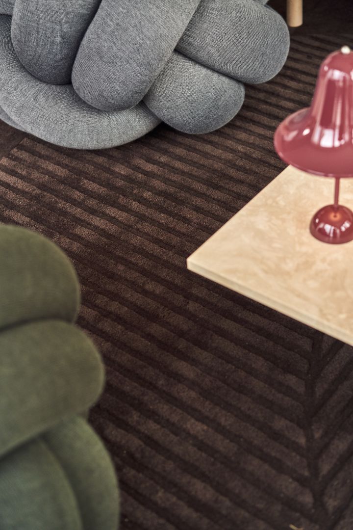 Close up of the Knot Cushion in grey XL and green medium with the ruby red table lamp from Verpan. 