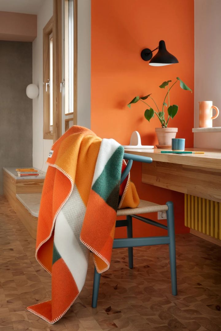 Orange is a strong colour in the interior colour trends 2024. Here you see the Mikkel throw in orange and green from Røros Tweed.